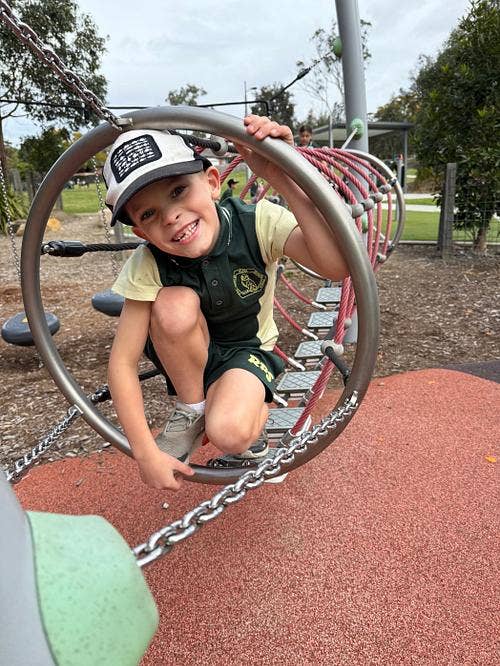 Student at the playground climbing through metal rings.