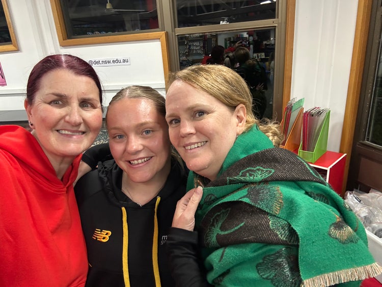 A picture of three female teachers looking at the camera close together smiling.