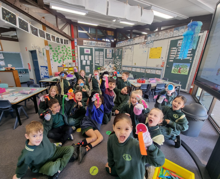 A group of students who have puppets on their hands putting some funny faces.