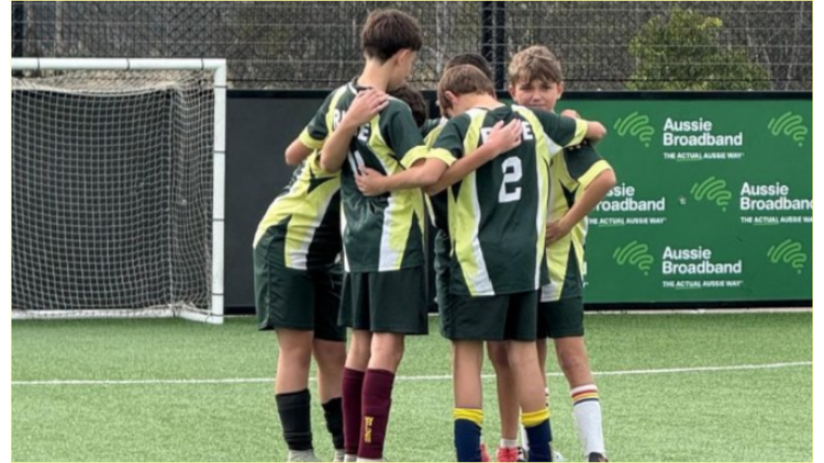 Group huddle on the soccer field with 6 boys