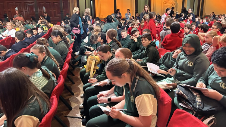 A group of students sitting on red chairs facing a stage at the sydney writers festival.
