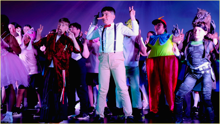 Students on stage doing a musical. Students are dressed in a range of costumes which on wearing a carrot on his nose.